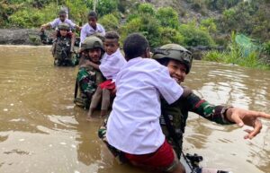 Prajurit Yonif 432 Kostrad Bantu Anak-anak Menyeberangi Sungai di Hari Anak Nasional