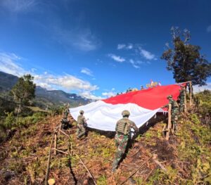 Satgas Yonif 323 Buaya Putih Kibarkan Bendera Raksasa di Atas Ketinggian Bukit Cakra Papua